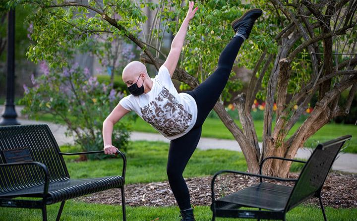 BW dance student holding a post next to an outdoor bench